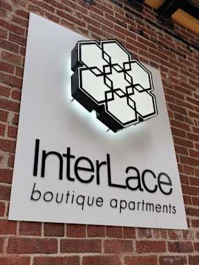 A sign for InterLace boutique apartments is displayed on a brick wall.