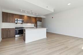 A kitchen with a white island and wooden cabinets.