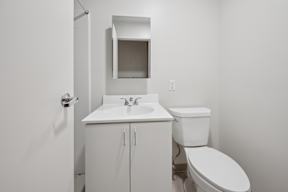 A white bathroom with a toilet, sink and cabinet.