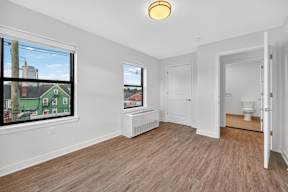 A room with a window overlooking a green house.