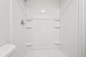 A white bathroom with a toilet and a shower stall.