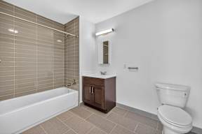 A white toilet sits next to a white bathtub in a bathroom.