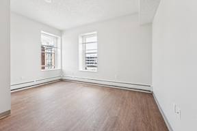 A room with wooden floors and two windows.
