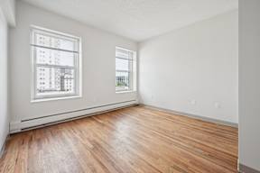 A room with wooden floors and two windows.