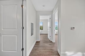 A long hallway with white doors and wood floors.