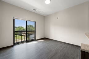 an empty living room with a balcony and wood flooring