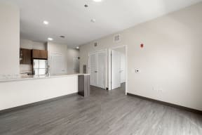 a renovated living room and kitchen with white walls and wood floors