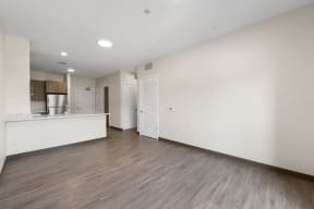 an empty living room and kitchen with white walls and wood floors