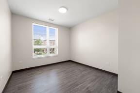 an empty living room with wood floors and a window