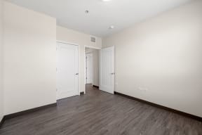 a bedroom with white walls and wood floors