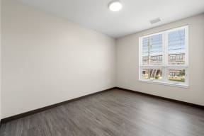 the living room of a house with a large window and wood floors