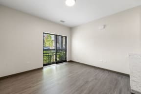 an empty living room with a sliding glass door to a balcony