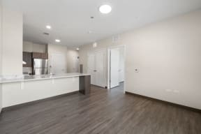 a renovated living room and kitchen with white walls and wood floors