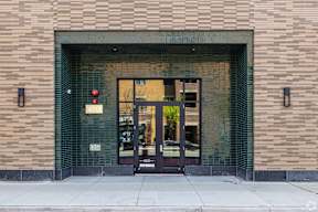 The front of a building with a glass door and a brick wall.