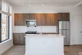A kitchen with white countertops and wooden cabinets.