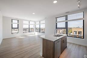 A modern kitchen with wooden floors and a large window overlooking the city.