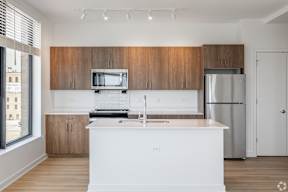 A kitchen with white countertops and wooden cabinets.
