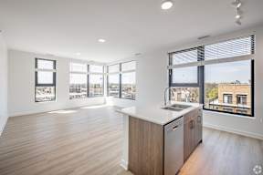 A kitchen with a wooden floor and a large window overlooking a cityscape.