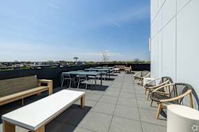 A rooftop patio with a white table and chairs.
