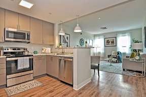 A modern kitchen with wooden floors and stainless steel appliances.
