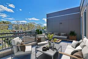 A balcony with a table and chairs overlooking a cityscape.
