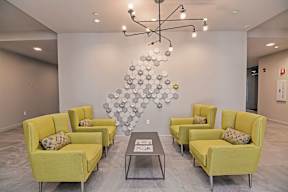 A room with a chandelier, yellow chairs, and a grey table.