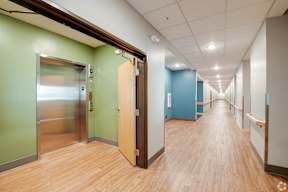 A long hallway with a wooden floor and doors on either side.