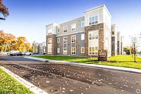 A modern apartment building with a parking lot in front.