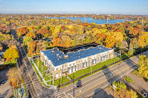 A large building with a lot of windows is surrounded by trees with autumn leaves.