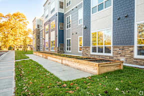A modern building with a blue and grey exterior and a wooden planter box in front.