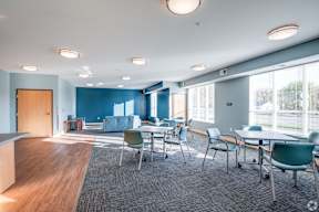 A room with blue walls and a carpeted floor with chairs and tables.