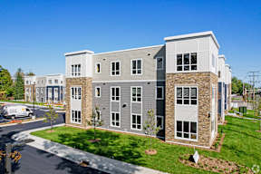 A modern apartment complex with a mix of grey and white buildings.