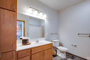 A bathroom with a toilet, sink, and mirror.
