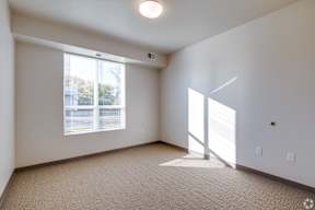 A room with a carpeted floor and a window with blinds.