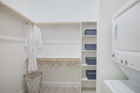a laundry room with a washer and dryer and a closet with hangers