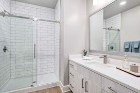 A white bathroom with a walk-in shower and double sink vanity.