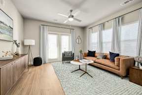 A living room with a brown couch, a white coffee table, and a wooden floor.