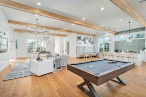 A billiard table is in the middle of a spacious room with a pool table.
