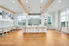 A modern kitchen with wooden floors and white bar stools.