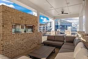 A patio with a couch, table, and a brick wall.
