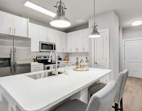 A modern kitchen with a white table and grey chairs.