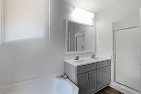 A white bathroom with a tub, sink, and mirror.