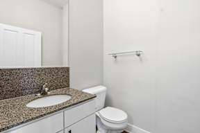 A bathroom with a toilet, sink, and mirror.