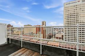 A white railing on a balcony with a view of a cityscape.