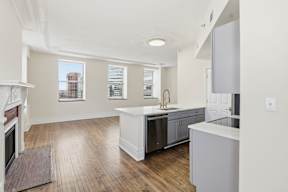 A kitchen with a white counter top and wooden floors.