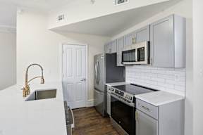 A kitchen with a white counter top and stainless steel appliances.