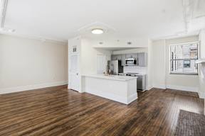 A kitchen with white cabinets and a wooden floor.