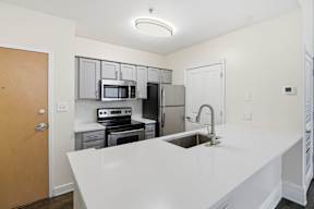 A kitchen with white countertops and stainless steel appliances.
