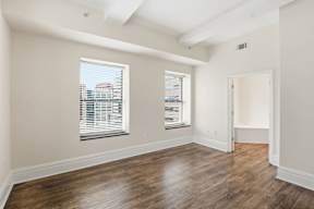 A room with wooden floors and a window with blinds.