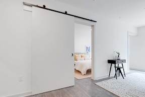 a white bedroom with a white bed and a white desk with a black chair
